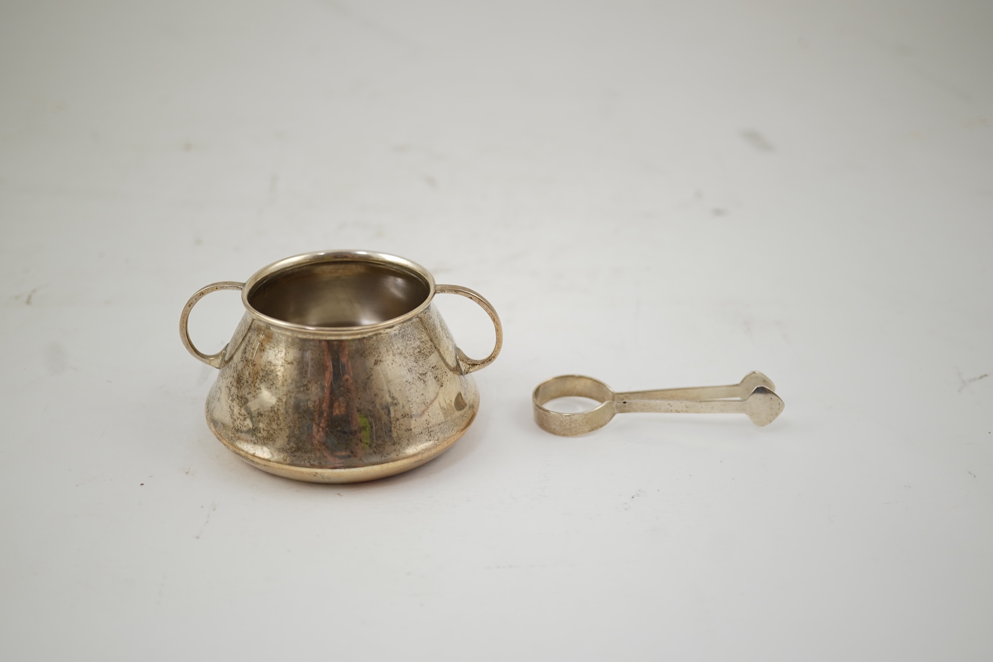 An Edwardian silver bachelor's two handled sugar bowl and matching sugar tongs, by Liberty & Co